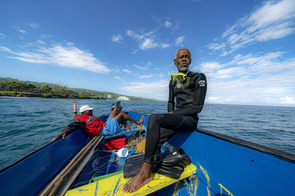 Everton Simpson, right, sits on a boat in-between dives on the White River Fish Sanctuary with Mark Lobban, left, Monday, Feb. 11, 2019, in Ocho Rios, Jamaica. More than a dozen grassroots-run fish sanctuaries and coral nurseries have sprung up on the island in the past decade. (AP Photo/David J. Phillip)