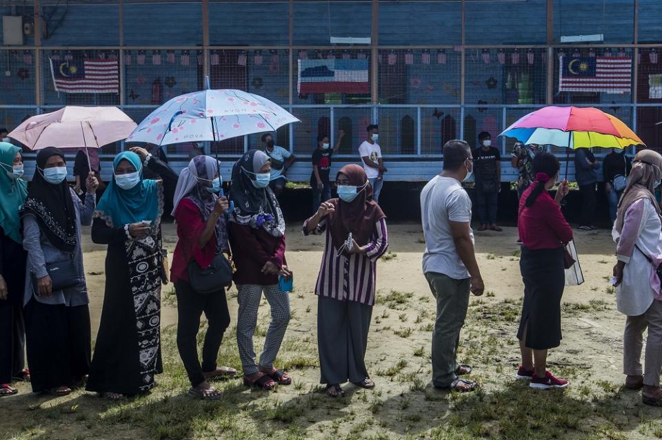 Voters wearing protective masks queue up to cast their votes during the Sabah state election in SK Pulau Gaya September 26, 2020.