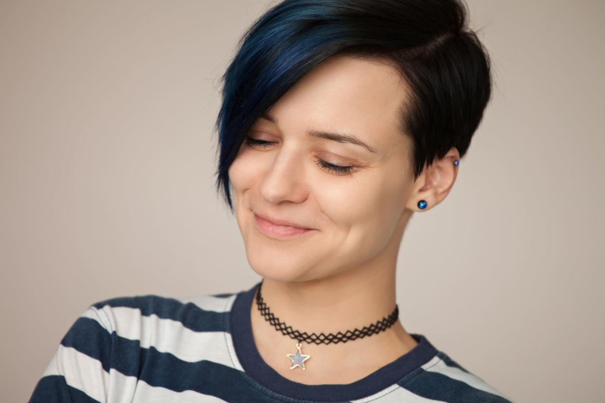 Studio portrait of an attractive 30 year old woman in a striped t-shirt on a beige background