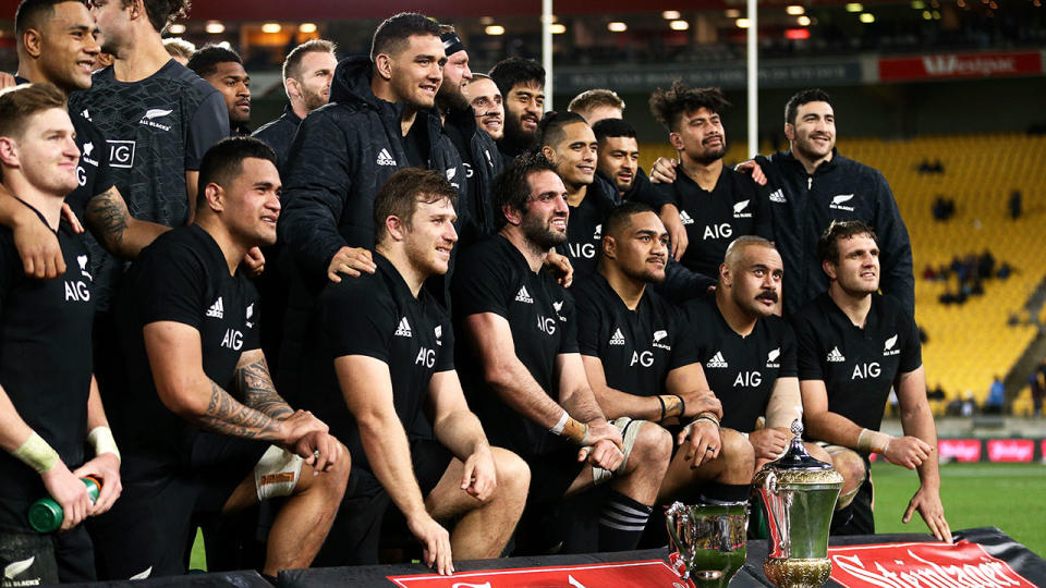 Pictured here, the All Blacks squad pose together with two of their trophies.