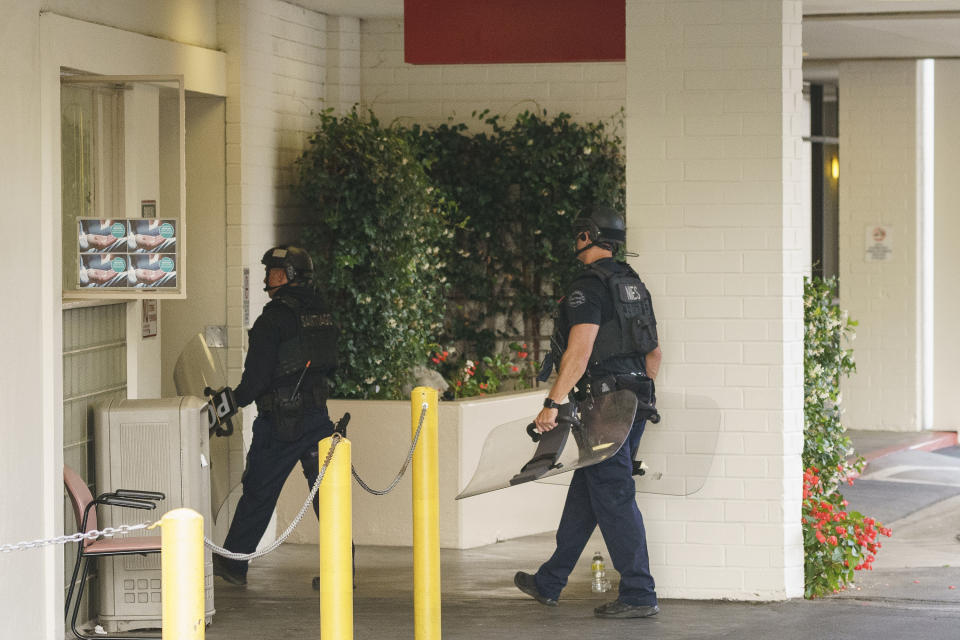 Los Angeles police enter a door at Encino Hospital Medical Center in Los Angeles on Friday, June 3, 2022. A man stabbed a doctor and two nurses inside a hospital emergency ward and remained inside a room for hours before police arrested him, authorities said. (AP Photo/Damian Dovarganes)
