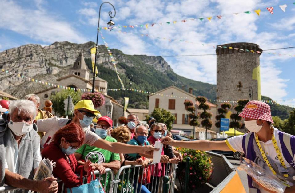 An employee distributes face masks to spectators prior to the 4th stage between Sisteron and Orcieres-Merlette.