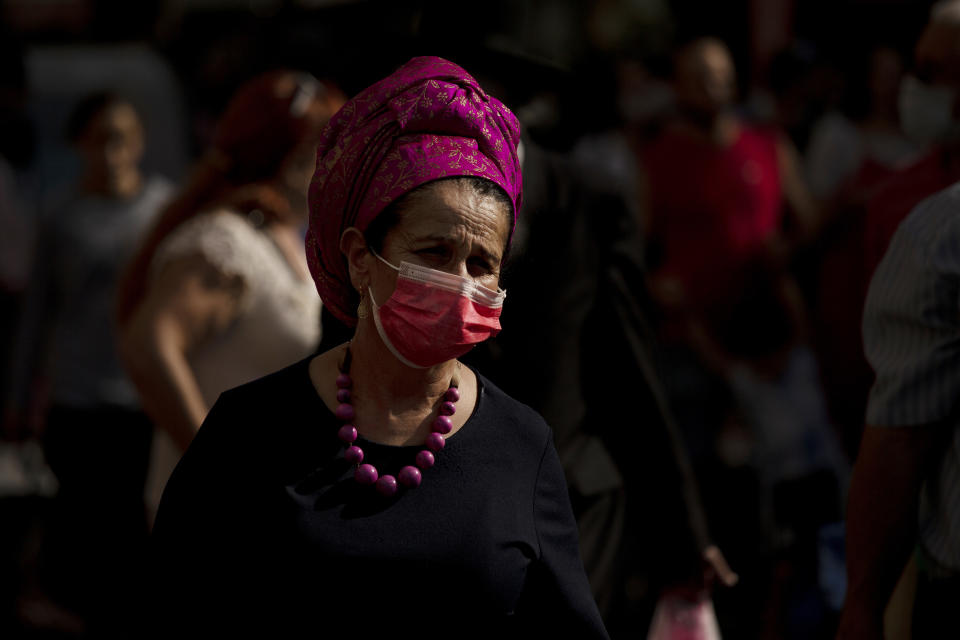 A woman wears a mask as a measure of protection against the coronavirus, as she shops for Shabbat at Machane Yehuda Market in Jerusalem, Friday, Aug. 13, 2021. Israel is expanding its coronavirus booster shot program to people over age 50. (AP Photo/Maya Alleruzzo)