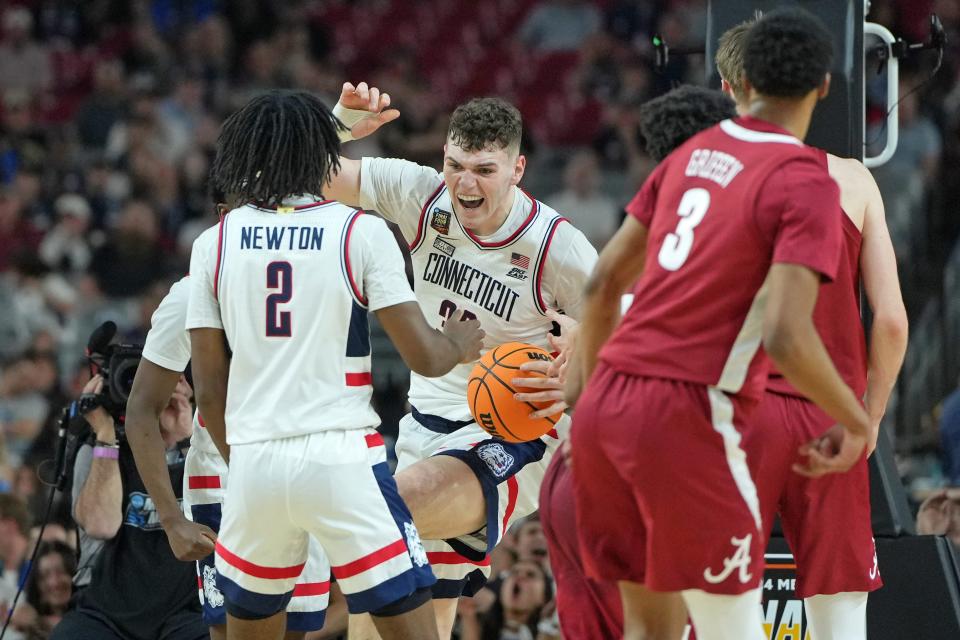 Connecticut center Donovan Clingan (32) celebrates after dunking against Alabama during the Final Four of the 2024 NCAA men's tournament at State Farm Stadium.