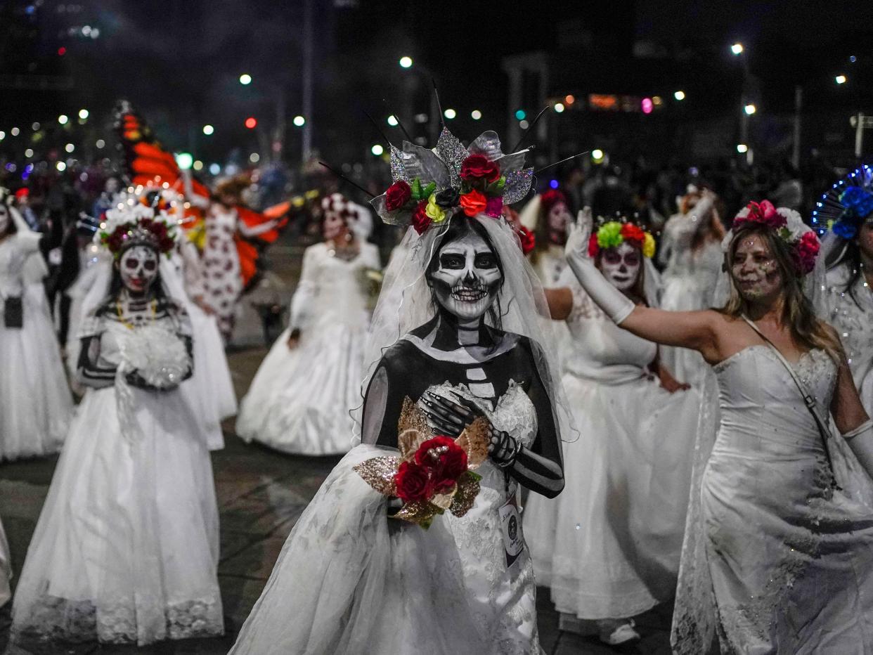 People dressed as Mexico's iconic "Catrinas" march in the Grand Procession of the Catrinas, part of upcoming Day of the Dead celebrations in Mexico City, Sunday, Oct. 23, 2022.