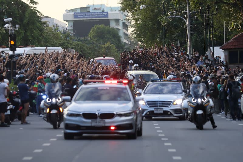 The royal motorcade carrying Thailand's Queen Suthida and Prince Dipangkorn drives past a group of anti-government demonstrators in front of Government House in Bangkok