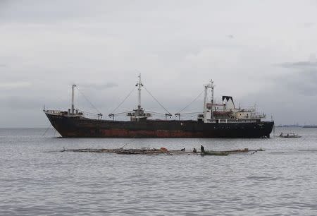 Fishermen recover a destroyed fish pen in front of a cargo ship swept near the Roxas Boulevard at the height of Typhoon Kalmaegi in Manila September 15, 2014. REUTERS/Erik De Castro