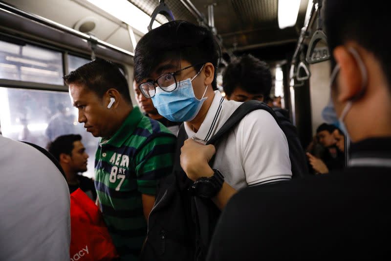 A passenger wearing a protective mask attempts to get off the train in Manila