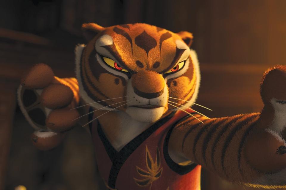 An animated tiger is stood in a golden-lit room, ready for kung fu battle, with his right arm pulled back and his left arm straight in front of him. He has a look of angry determination on his face, look straight ahead challengingly.
