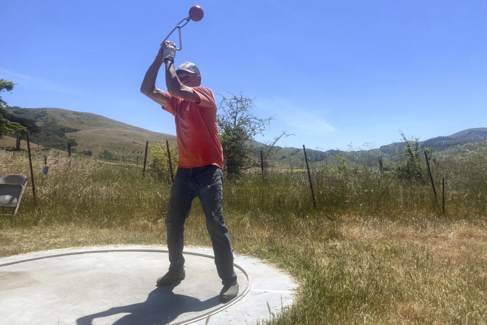 Rancher Mike Gale practices with a piece of throwing equipment in Petaluma, Calif., on May 24, 2022. Gale, 80, installed a track and field throwing circle on his sprawling property in Petaluma, California, so he and some friends could practice throwing the discus and other equipment. "I’d like to be competing in my 90s," Gale says. "Why not?" (AP Photo/Laura Ungar)