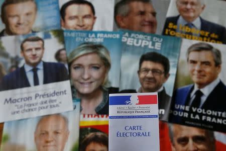 A photo illustration shows a French voter card in front of pictures of the candidates for the French presidential election, April 22, 2017. REUTERS/Pascal Rossignol/Illustration