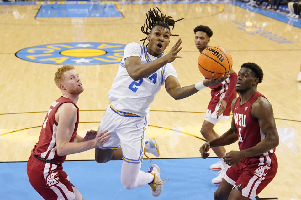 UCLA guard Dylan Andrews, second from left, shoots as Washington State guard Jabe Mullins, left, and guard TJ Bamba, right, defend during the first half of an NCAA college basketball game Saturday, Feb. 4, 2023, in Los Angeles. (AP Photo/Mark J. Terrill)