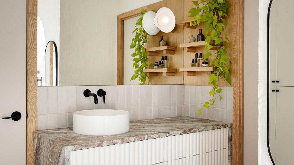  Bathroom vanity in marble with fluted cabinet doors, long mirror and plant. 