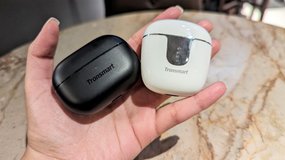 Tronsmart Onyx Ace Pro wireless earbuds and Tronsmart Onyx Pure earbuds inside their cases held in one hand