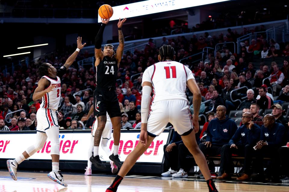 Cincinnati Bearcats guard Jeremiah Davenport (24) hits a 3-point shot over Detroit Mercy Titans guard Kyle LeGreair (2) in the first half of the NCAA men’s basketball game at Fifth Third Arena in Cincinnati on Wednesday, Dec. 21, 2022. 