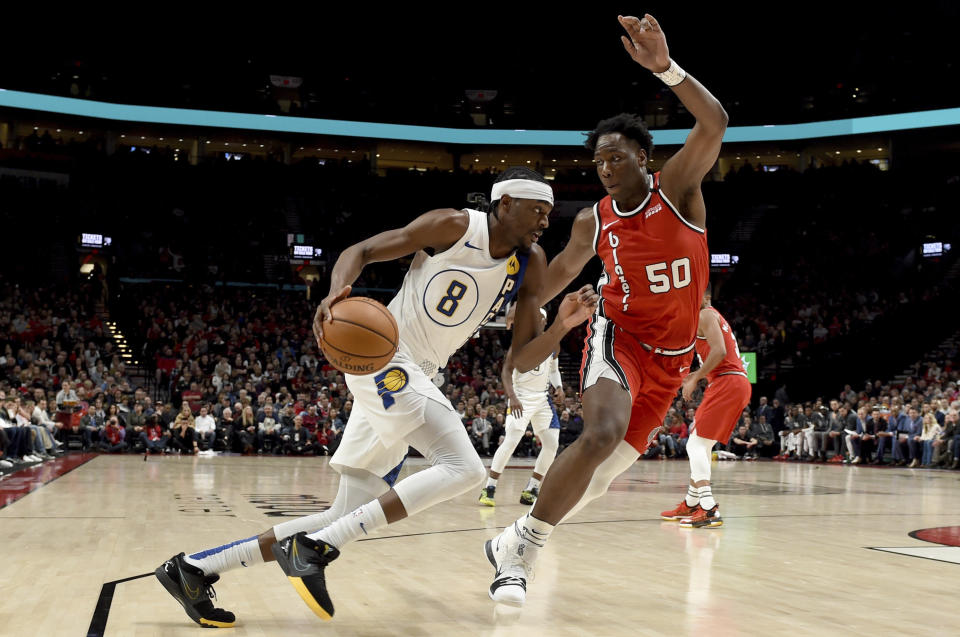 Indiana Pacers forward Justin Holiday, left, drives to the basket on Portland Trail Blazers forward Caleb Swanigan, right, during the first half of an NBA basketball game in Portland, Ore., Sunday, Jan. 26, 2020. (AP Photo/Steve Dykes)