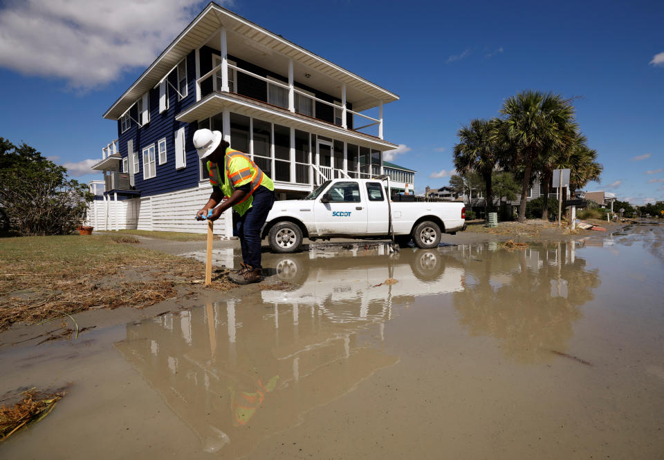 Seorang pekerja Departemen Transportasi Carolina Selatan menemukan saluran air yang tersumbat di jalan yang banjir setelah Badai Ian melanda Pulau Pawleys, Carolina Selatan, AS, 1 Oktober 2022. REUTERS/Jonathan Drake