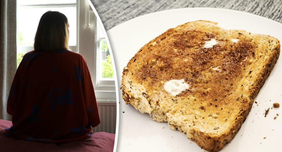 A woman sitting on a bed in the shadows from behind and a piece of buttered toast.