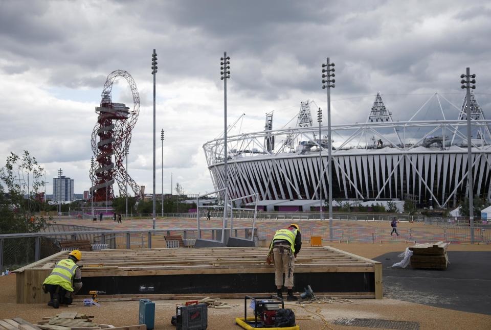 Construction crews work outside the Olympic Stadium as preparations continue for the 2012 Summer Olympics, Sunday, July 15, 2012, in London. At left is the Orbit. (AP Photo/Jae Hong)