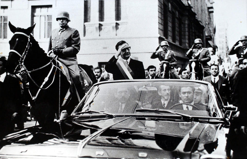 FILE - Chilean President Salvador Allende salutes from an open vehicle as General Augusto Pinochet rides on horseback at left in Santiago, Chile, May 21, 1972. (AP Photo/File)