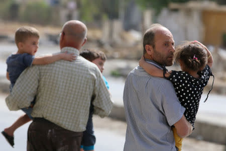 Men carry children away from a damaged site after airstrikes on the rebel held al-Qaterji neighbourhood of Aleppo. REUTERS/Abdalrhman Ismail