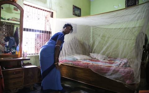 Meenakhi Maharana demonstrates the correct use of a bed net - Credit: Catherine Davison