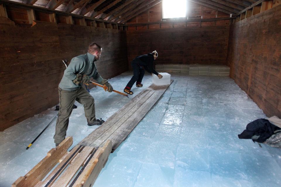 Douglas Adams, left, and Parker Hansen stacks ice in the ice house at the Rockywold-Deephaven Camp in Holderness, N.H. Thursday Jan. 9, 2014. For more than a century ice from Squam Lake has been used to keep ice boxes cool for summer residents at the camp. (AP Photo/Jim Cole)