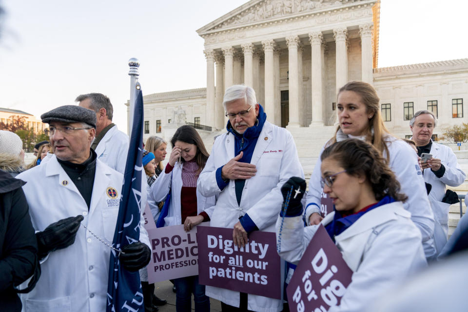 Anti-abortion healthcare workers, wearing doctors uniforms, pray together in front of the U.S. Supreme Court, Wednesday, Dec. 1, 2021, in Washington, as the court hears arguments in a case from Mississippi, where a 2018 law would ban abortions after 15 weeks of pregnancy, well before viability. (AP Photo/Andrew Harnik)