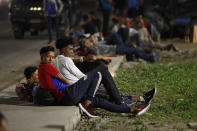 Migrants hoping to reach the distant U.S. border rest on the side of a highway, one kilometer from a police blockade, on the outskirts of San Pedro Sula, Honduras, Wednesday, Jan. 13, 2021. About 200 migrants began walking toward the border with Guatemala, two days before a migrant caravan was scheduled to depart the city. (AP Photo/Moises Castillo)