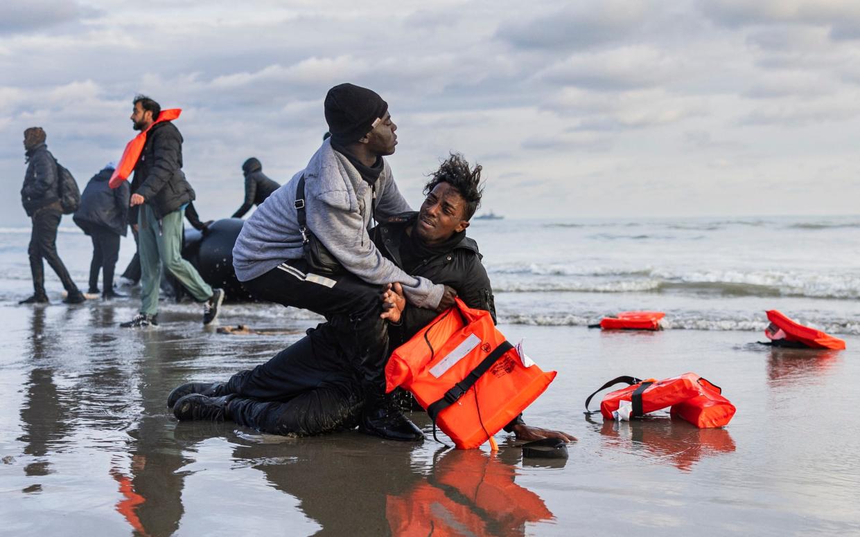 A Sudanese migrant react after leaving a smuggler's boat which was punctured with a knife by French police officers to prevent migrants from embarking in an attempt to cross the English Channel