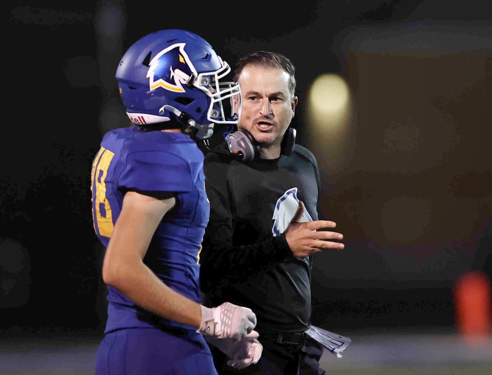 Madeira head coach Chris Stewart talks with Carson Cravaack (18) earlier in the season. The Mustangs advanced to the Division V regional semifinals with a win over Chillicothe Zane Trace Friday.