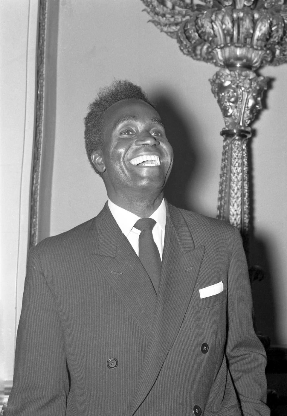 FILE - In this Dec. 5, 1960 file photo, Kenneth Kaunda, then leader of the United National Independence Party in the then Northern Rhodesia, now Zambia, laughs as he poses on arrival at Lancaster House, London for the opening by British Prime Minister Harold Macmillan of the Central African Federal Review Conference. Zambia’s first president Kenneth Kaunda has died at the age of 97, the country's president Edward Lungu announced Thursday June 17, 2021. (AP Photo/Laurence Harris, File)