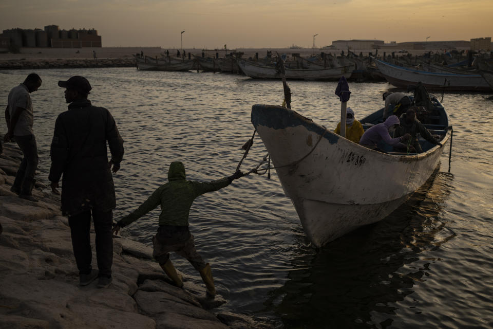 Men prepare to dock a fishing boat, known as pirogue, at the port in Nouadhibou, Mauritania, Saturday, Nov. 27, 2021. (AP Photo/Felipe Dana)