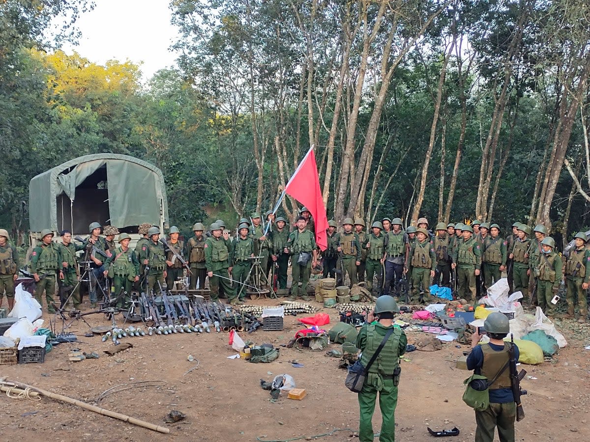 Members of the Myanmar National Democratic Alliance Army pose for a photograph with the weapons allegedly seized from the Myanmar’s army outpost on a hill in Chinshwehaw town, Myanmar (AP)