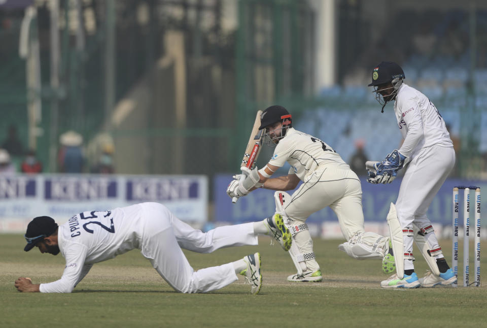 New Zealand's captain Kane Williamson looks on an India's Cheteshwar Pujara, left, stops the ball during the day three of their first test cricket match in Kanpur, India, Saturday, Nov. 27, 2021. (AP Photo/Altaf Qadri)