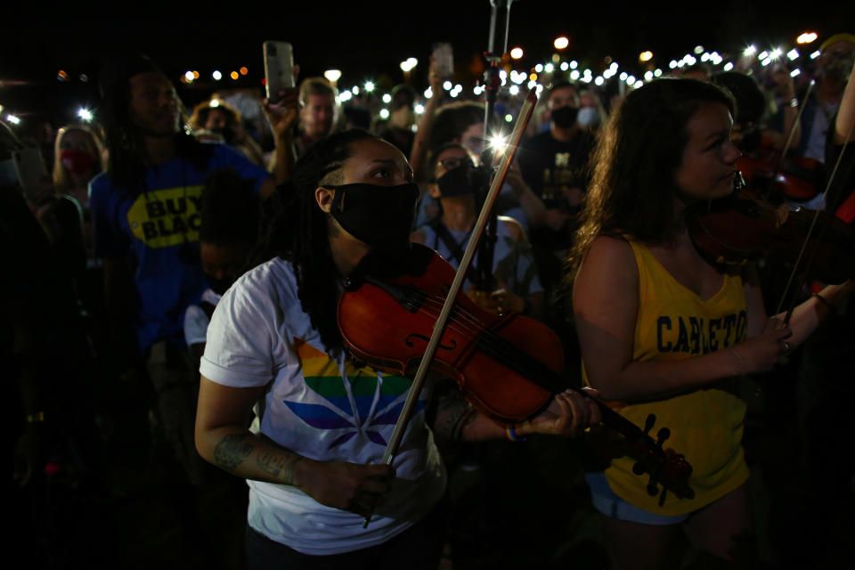 At a vigil in Aurora, Colorado, on June 27, 2020,Valerie Reives plays the viola while protesters shine their mobile phone lights to honor Elijah McClain who, when alive, would play his violin at animal shelters because he thought the kittens were lonely. / Credit: KEVIN MOHATT / REUTERS