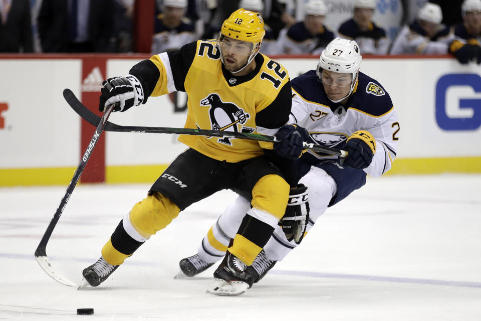 Pittsburgh Penguins' Dominik Simon (12) is defended by Buffalo Sabres' Curtis Lazar (27) during the second period of an NHL hockey game in Pittsburgh, Saturday, Feb. 22, 2020. (AP Photo/Gene J. Puskar)