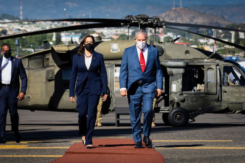 La vicepresidenta de Estados Unidos, Kamala Harris, camina por una alfombra roja con el embajador Ramón Valladares, jefe de protocolo de Honduras, en Palmerola, Honduras.