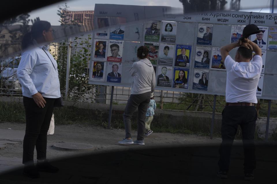 FILE - Residents look at candidates posters two days before polls open in Ulaanbaatar, Mongolia on June 26, 2024. Even in a busy year of elections, the next few days stand out. Voters go to the polls over the next week in fledgling democracies like Mauritania and Mongolia, in the Islamic Republic of Iran and in the stalwart democracies of Britain and France. (AP Photo/Ng Han Guan, File)