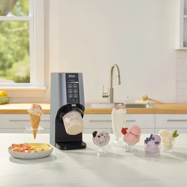 Ninja's latest ice cream maker located on a kitchen countertop next to different desserts. 
