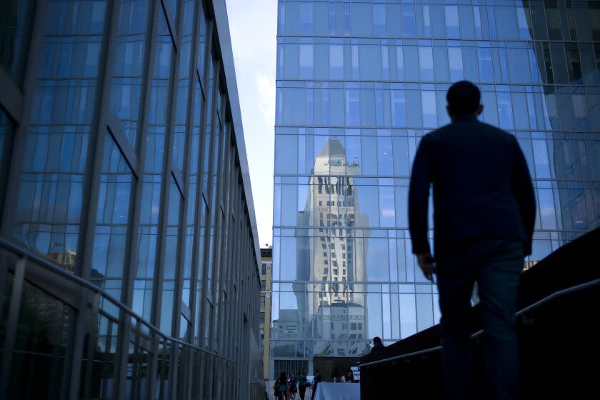 A guest arrives for a reception celebrating Latino Heritage Month as Los Angeles City Hall is reflected on the glass facade of the LAPD headquarters on Thursday, Sept. 18, 2014, in Los Angeles. (AP Photo/Jae C. Hong)