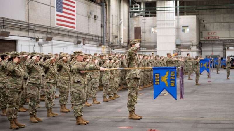 Military members saluting a flag