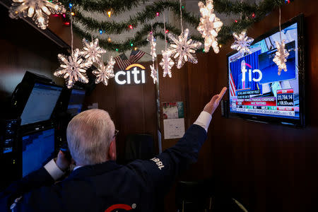 A trader works inside his booth as a screen displays U.S. Federal Reserve Chairperson Jerome Powell's news conference on the floor of the New York Stock Exchange (NYSE) in New York, U.S., December 19, 2018. REUTERS/Brendan McDermid