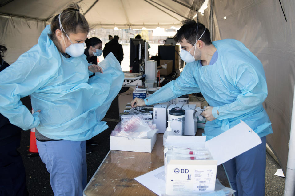 Medical workers prepare for the opening of a COVID-19 testing facility in Camden, N.J., Wednesday, April 1, 2020. The new coronavirus causes mild or moderate symptoms for most people, but for some, especially older adults and people with existing health problems,  it can cause more severe illness or death.(AP Photo/Matt Rourke)