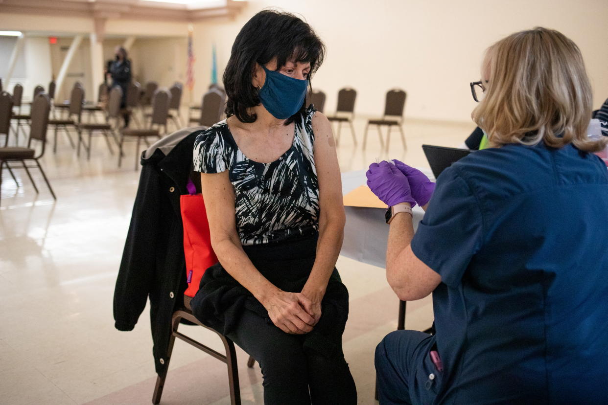 A woman who is immunocompromised speaks with a nurse after receiving a second booster shot of the COVID-19 vaccine in Waterford, Michigan.