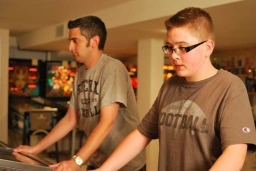 Pinball wizards Joshua Henderson (R) and Josh Sharpe (L) play on August 16, 2011 in Sharpe's basement, which houses 17 pinball machines. They are among a growing number of pinball enthusiasts who are keeping the game alive even after arcades were emptied by computer games and home systems like Ninetendo