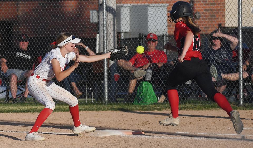 Ballard second baseman Maggie Mortensen (27) tries to make the catch as North Polk's Lauren Ausborn (8) reaches the first base safely during the third inning of the Bombers' 3-2 loss at Gary Telford Field Tuesday, June 28, 2022, in Huxley, Iowa.