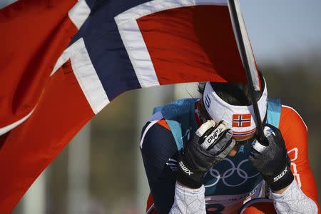 Cross-Country Skiing - Pyeongchang 2018 Winter Olympics - Women's 30km Mass Start Classic - Alpensia Cross-Country Skiing Centre - Pyeongchang, South Korea - February 25, 2018 - Gold medallist Marit Bjoergen of Norway reacts while holding her national flag. REUTERS/Carlos Barria