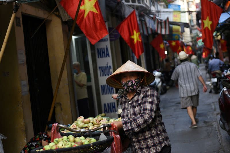 FILE PHOTO: A vendor walks in an alley decorated with national flags ahead of the upcoming elections in Hanoi