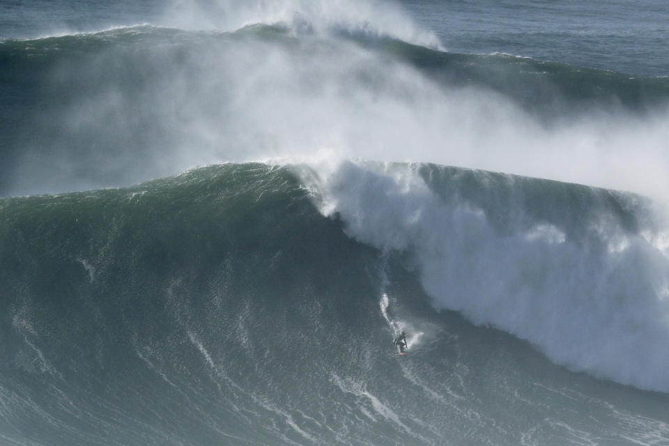 A surfer drops down a wave during a tow surfing session at Praia do Norte or North Beach in Nazare, Portugal, Thursday, Oct. 29, 2020. A big swell generated earlier in the week by Hurricane Epsilon in the North Atlantic, reached the Portuguese west coast drawing big wave surfers to Nazare. (AP Photo/Pedro Rocha)